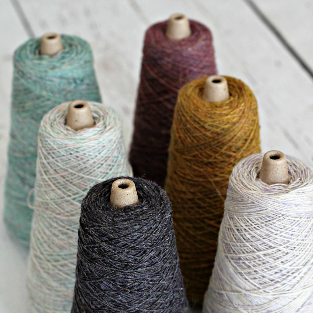 Set of yarn cones in various colors on a wooden surface