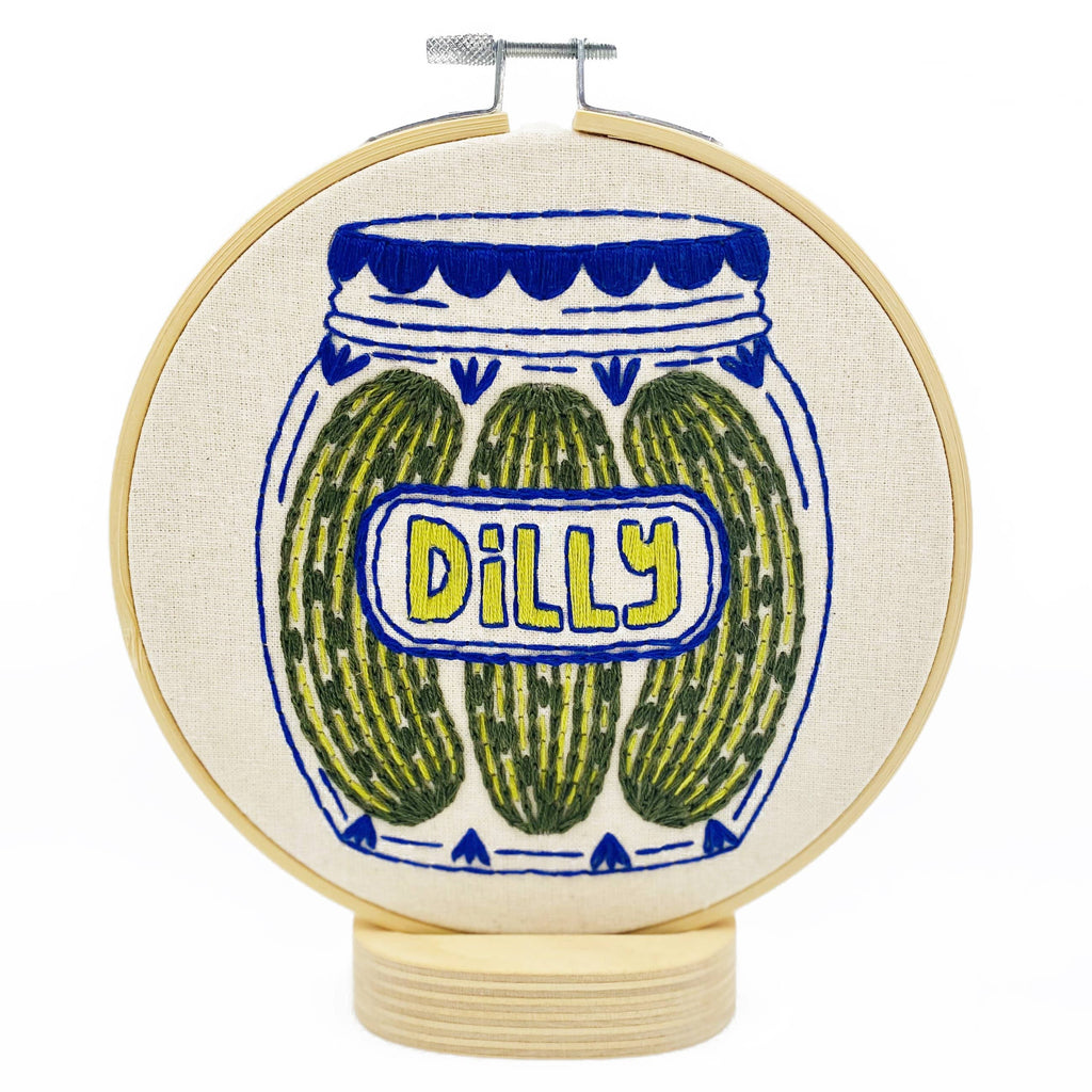 Embroidery hoop with a jar of pickles design and 'Dilly' text on a white background