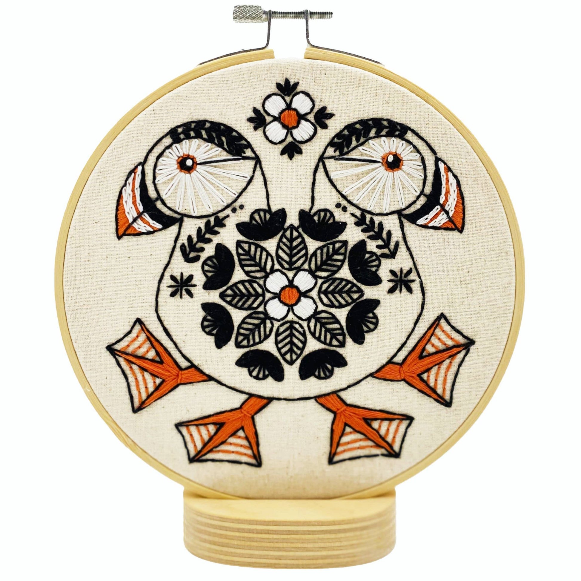 Embroidery hoop with a design featuring a puffin, predominantly in beige, with a darker beak and darker background.